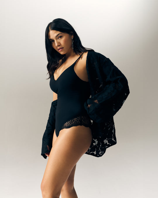 Val voor onze zwarte kanten bodysuit, een glamoureus en verfijnd stuk. Het combineert elegantie en comfort en laat je figuur beter uitkomen met een sensuele, moderne look.